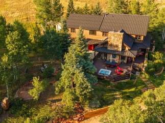 Experience luxury mountain living in this stunning home, featuring a spacious deck with a hot tub and outdoor dining area perfect for entertaining.