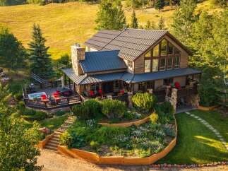 Experience luxury mountain living in this stunning home, featuring a spacious deck with a hot tub and ample seating, perfect for entertaining or relaxing amidst breathtaking natural surroundings.