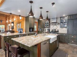 Experience rustic charm in this spacious kitchen featuring custom green cabinetry and a large granite island perfect for entertaining.