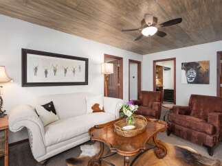 Experience rustic charm in this inviting living room, featuring a plush cream sofa adorned with cowhide pillows and a striking framed artwork of elk.