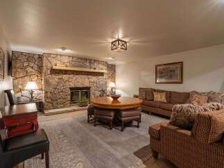Cozy up by the stunning floor-to-ceiling stone fireplace in this inviting living room, perfect for gathering with loved ones.
