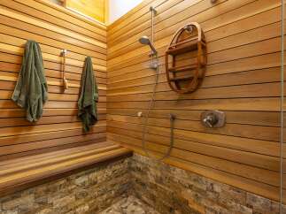 Experience ultimate relaxation in this spa-like shower featuring warm cedar wood paneling and a built-in bench.