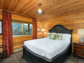 Experience rustic charm in this cozy bedroom, featuring warm wood-paneled walls and a vaulted ceiling.