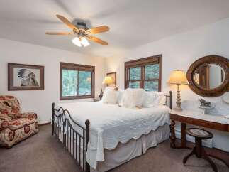 Experience rustic charm in this inviting bedroom, featuring a comfortable queen-size bed adorned with plush white bedding and decorative pillows.