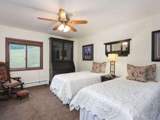 This charming bedroom features two comfortable twin beds adorned with elegant white quilted comforters and decorative floral pillows.