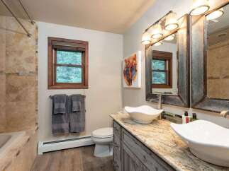 This charming bathroom features a spacious vanity with two vessel sinks and granite countertops, perfect for a couple.