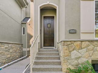 Welcome to this charming home featuring a beautifully crafted dark wood front door with decorative glass accents, set within an arched entryway.