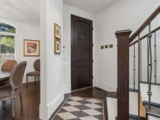 Step into a grand entryway featuring a dark wood door and a striking staircase with ornate metal railings.