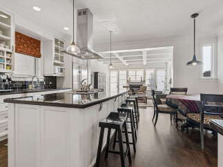This stunning open-concept kitchen features a large island with seating, sleek granite countertops, and a professional-grade range hood.