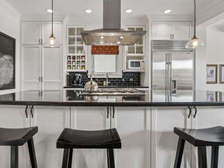 This modern kitchen boasts sleek black granite countertops and a matching backsplash, complemented by white custom cabinetry.