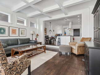 Experience sophisticated living in this open-concept home, featuring a stunning coffered ceiling and a seamless flow between the living area and a modern kitchen.