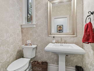 This powder room features elegant paisley wallpaper and a classic pedestal sink with ornate fixtures.
