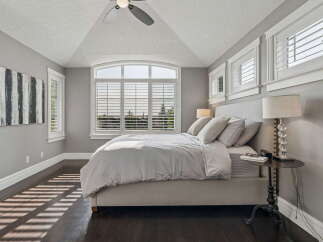 Experience serene living in this beautifully appointed bedroom, featuring a vaulted ceiling and a large arched window that floods the space with natural light.