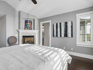 Experience luxury living in this stunning bedroom featuring a cozy fireplace and vibrant artwork.