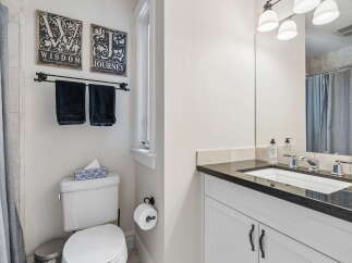 This bright and clean bathroom features a modern vanity with a granite countertop and a sleek undermount sink.
