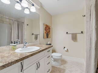 This bright and airy bathroom features a spacious vanity with a granite countertop and a large mirror, perfect for your morning routine.