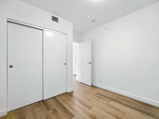 Step into this bright and airy room, featuring sleek sliding closet doors and a modern open doorway leading to another space.