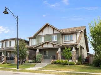 Discover this charming two-story home featuring a welcoming covered porch with stone accents and a spacious front yard.