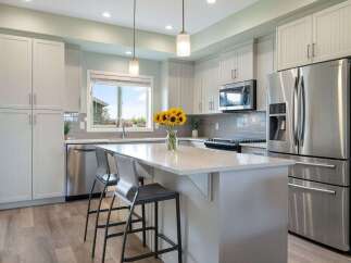 Discover this stunning modern kitchen featuring sleek white cabinetry, a spacious island with bar seating, and a beautiful subway tile backsplash.