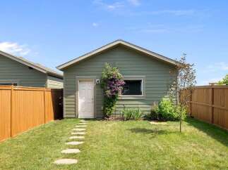 Discover this charming property featuring a detached garage with a classic white door and a large window, perfect for storage or a workshop.