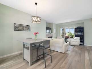 This open-concept living and dining area features a stylish high-top table with bar stools, perfect for casual meals or entertaining.