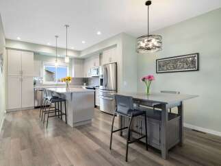 This modern kitchen boasts sleek white cabinetry and a spacious island, perfect for meal preparation and casual dining.