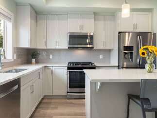 Experience modern living in this stunning kitchen, featuring sleek white cabinetry and a complementary grey subway tile backsplash.