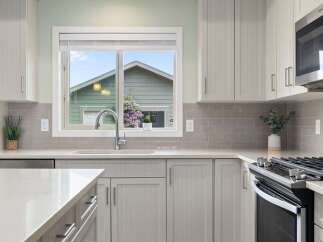 This modern kitchen features sleek, light gray cabinetry and a complementary subway tile backsplash.