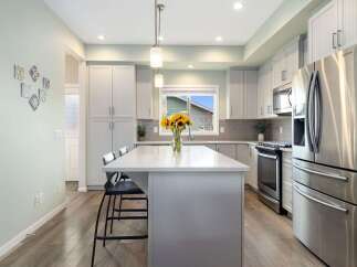 Experience modern living in this stunning kitchen, featuring sleek white cabinetry, a spacious quartz island with seating, and a beautiful subway tile backsplash.