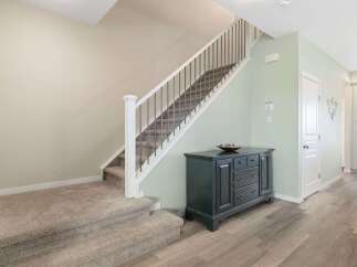 Step into this inviting entryway featuring a carpeted staircase with a modern railing, perfect for a cozy and elegant home.
