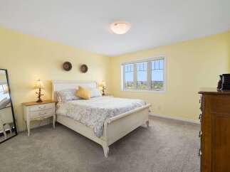 This charming bedroom features a comfortable queen-size bed with a floral-patterned comforter and a sunny yellow accent pillow.