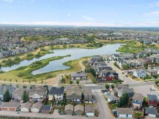 Discover this stunning aerial view of a modern suburban neighborhood, featuring a serene lake and meticulously designed homes.