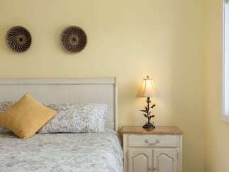 This charming bedroom features a comfortable bed adorned with a textured yellow accent pillow and a floral-patterned duvet.