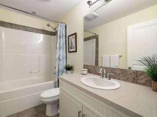 This bright and clean bathroom features a pristine white bathtub and toilet, complemented by a stylish blue and white patterned shower curtain.