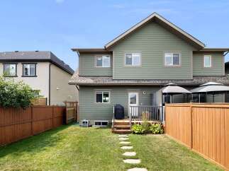 Enjoy outdoor living in this spacious backyard featuring a wooden deck and a stone pathway leading to a lush green lawn.