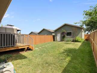 Enjoy outdoor living in this spacious backyard featuring a wooden deck perfect for entertaining and a well-maintained lawn.