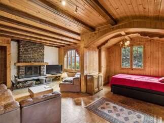 Experience rustic charm in this cozy living space featuring a prominent stone fireplace and warm wooden interiors.