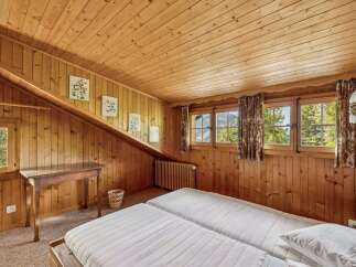 Experience rustic charm in this cozy wooden bedroom, featuring two comfortable beds perfect for a restful night's sleep.