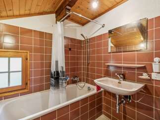 This charming bathroom features a classic bathtub with a shower curtain, perfect for relaxing baths or quick showers.