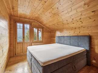 Experience rustic charm in this cozy wooden cabin bedroom, featuring a comfortable bed with a plush headboard.