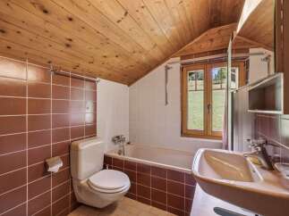 Experience rustic charm in this bathroom featuring warm wooden ceilings and rich brown tiled walls.