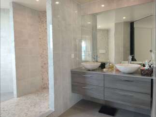 Experience modern luxury in this stunning bathroom featuring a spacious walk-in shower with elegant tiling and a chic double vanity.