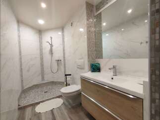 Experience modern luxury in this stunning bathroom featuring a spacious walk-in shower with elegant marble-look tiles and a pebble-stone floor.