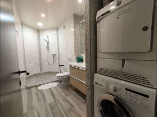 This modern bathroom features a spacious walk-in shower with marble-look tiles and a sleek vanity with ample storage.