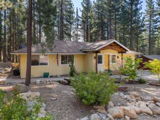 Nestled among tall pine trees, this charming yellow home offers a serene retreat.