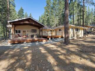 Experience serene living in this charming yellow home nestled among tall pine trees.