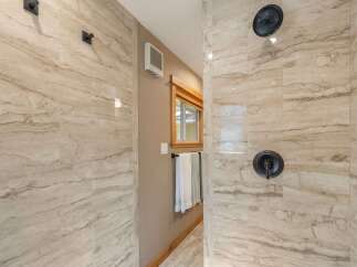 Experience luxury in this modern bathroom featuring a spacious walk-in shower with elegant travertine-look tile.