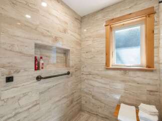 Experience luxury in this beautifully tiled shower featuring a built-in niche for convenient storage and a sturdy grab bar for added safety.
