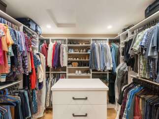 Discover this spacious walk-in closet, meticulously organized with ample shelving and hanging space for all your clothing and accessories.
