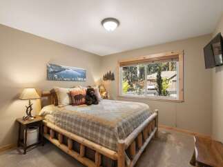 Experience rustic charm in this cozy bedroom, featuring a beautiful log bed and a scenic landscape painting above.